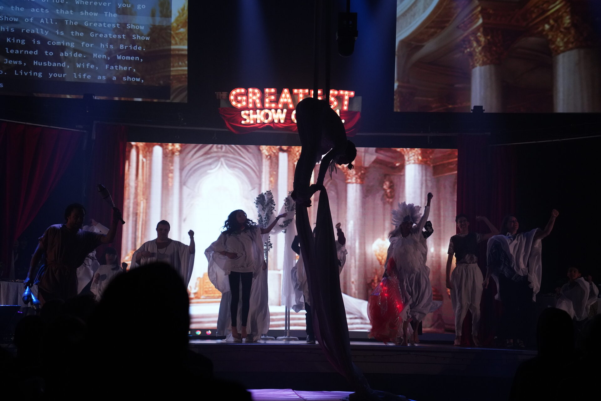 An aerial silk performer bowing center stage