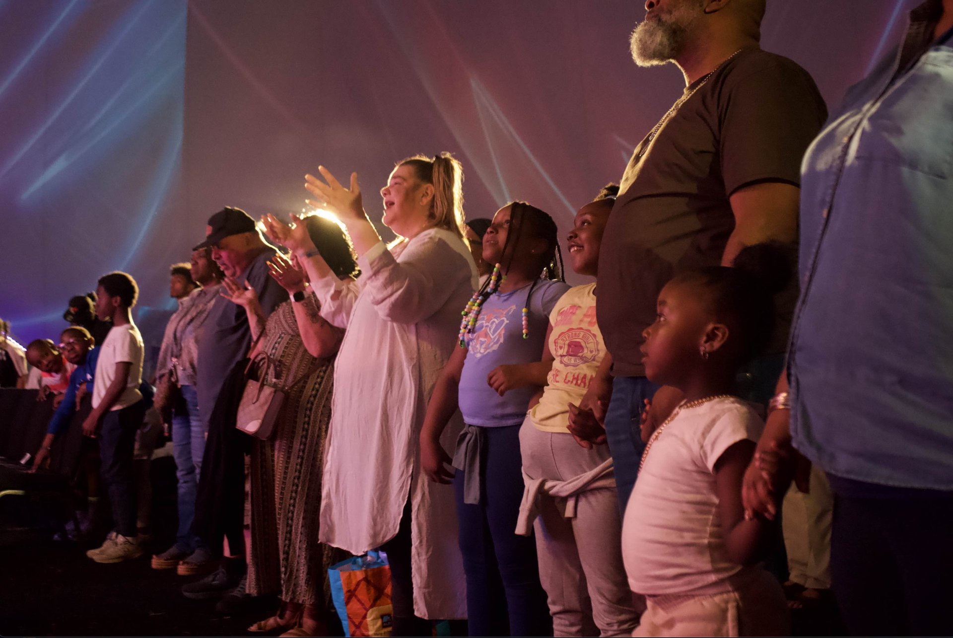 Families with hands raised, worshipping during the show