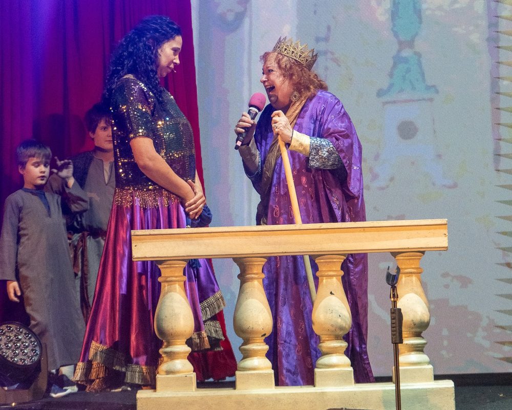 The queen and a singer share a dramatic moment on stage